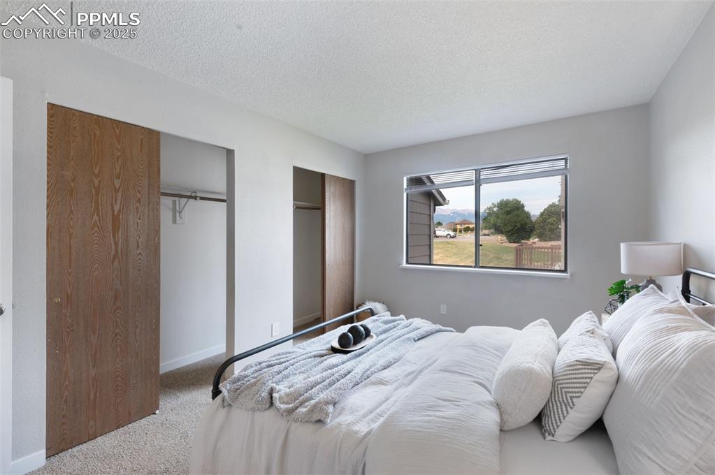 Image 14 of 26: Bedroom featuring carpet flooring, two closets, and a textured ceiling