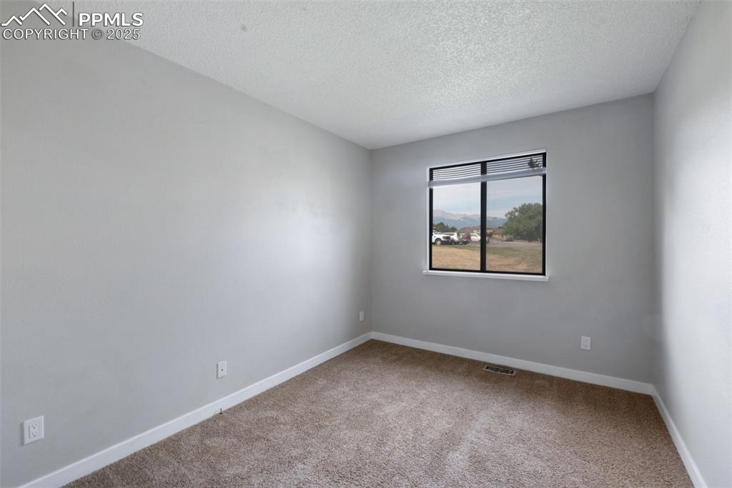 Image 15 of 26: Carpeted spare room featuring a textured ceiling and baseboards
