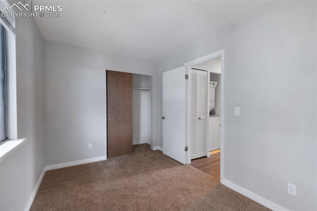 Image 18 of 26: Unfurnished bedroom featuring carpet, stacked washer / drying machine, a cl