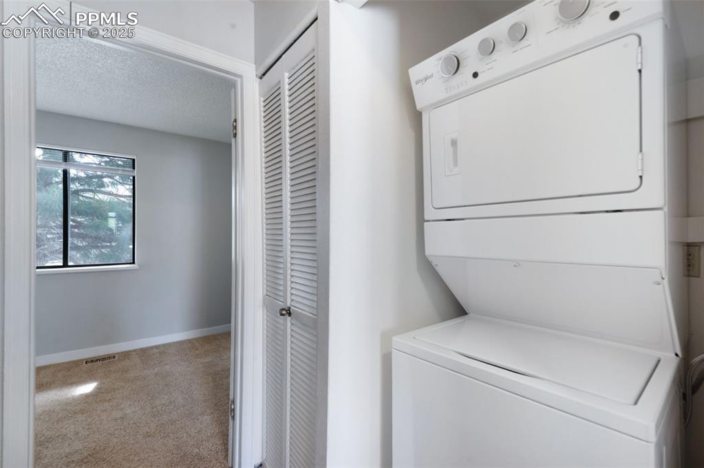 Image 20 of 26: Washroom with stacked washer / dryer, carpet floors, and a textured ceiling