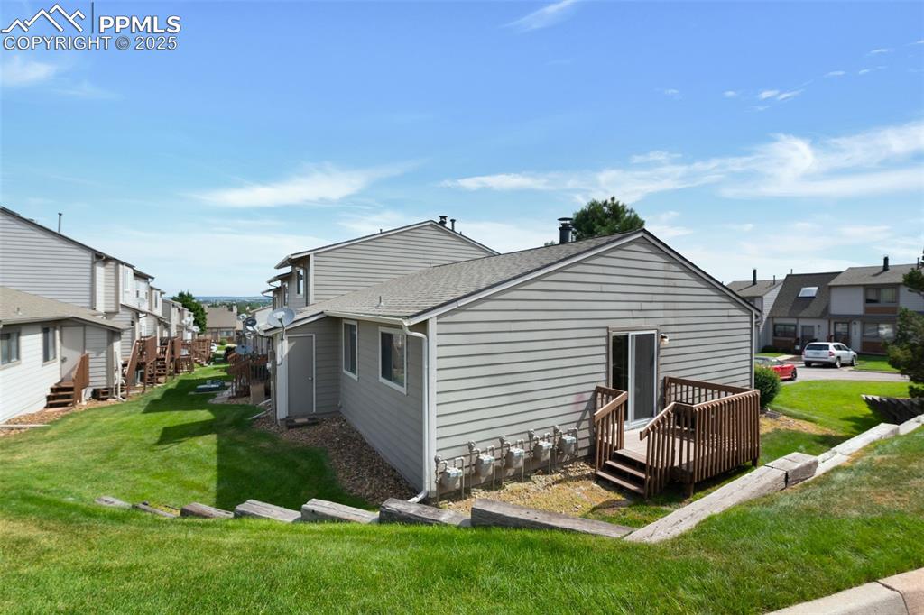 Image 22 of 26: Back of property with roof with shingles, a lawn, and a residential view
