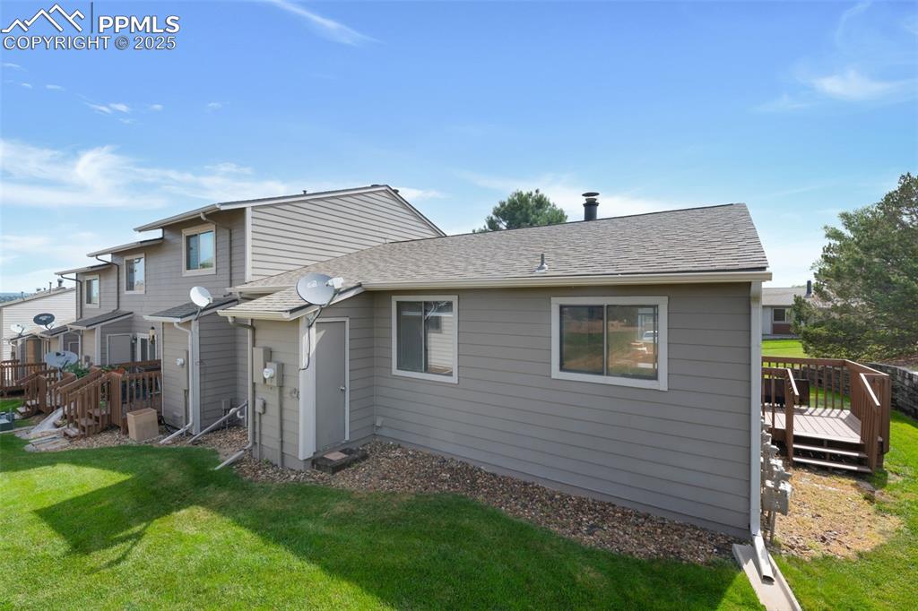 Image 24 of 26: Back of house with a wooden deck, roof with shingles, and a lawn
