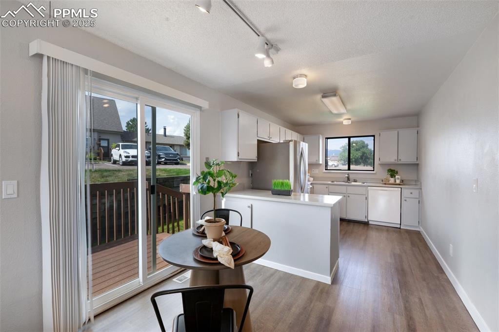 Image 3 of 26: Kitchen featuring wood finished floors, rail lighting, light countertops, w