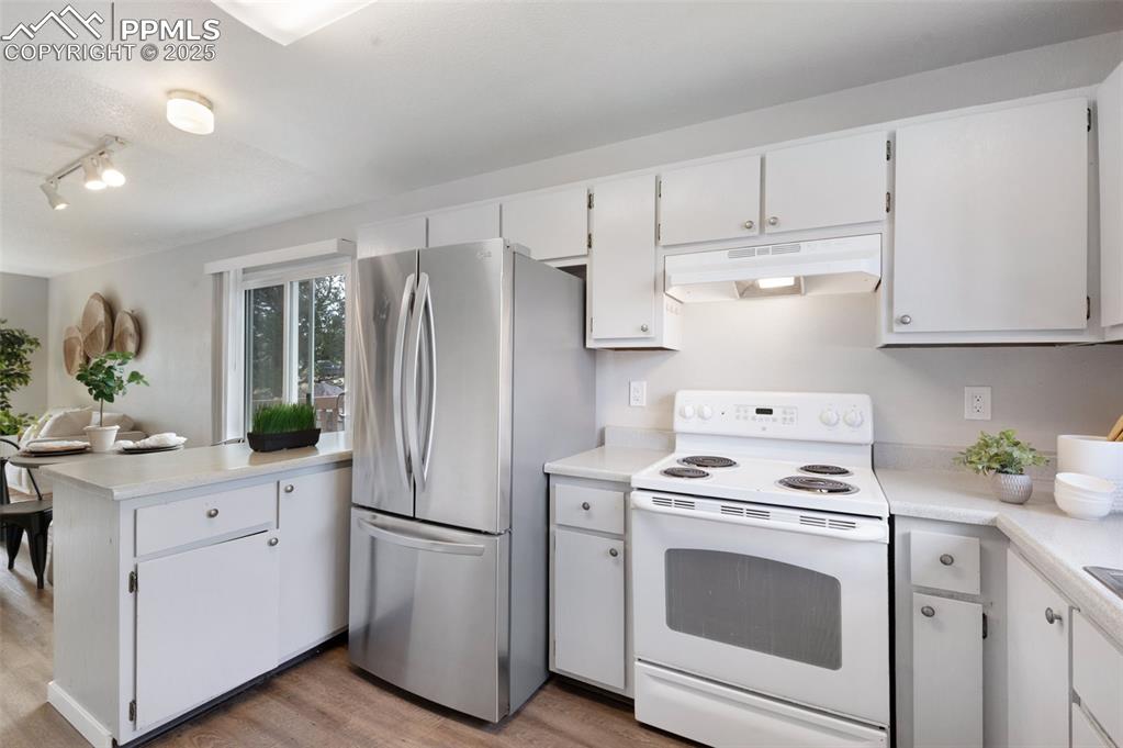Image 4 of 26: Kitchen featuring electric stove, a peninsula, light wood-style flooring, f