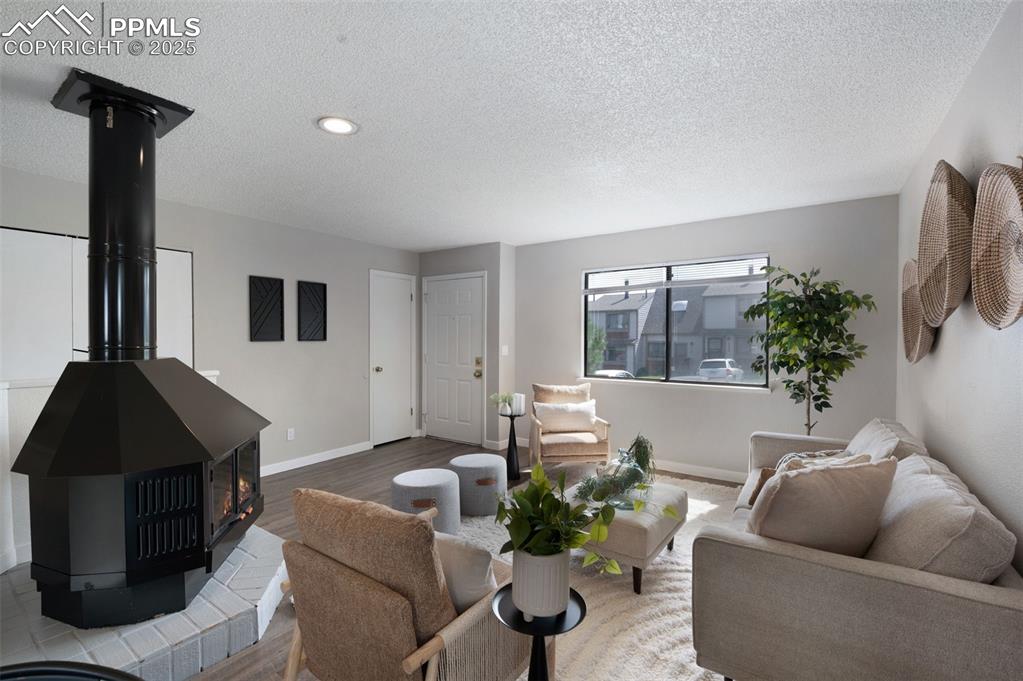 Image 5 of 26: Living area featuring a wood stove, a textured ceiling, wood finished floor