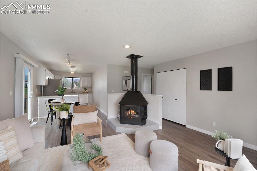 Image 7 of 26: Living area featuring wood finished floors, a wood stove, and recessed ligh