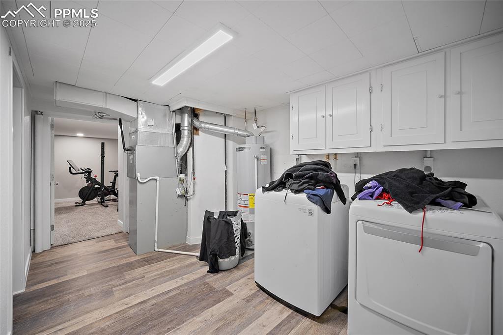 Image 8 of 34: Laundry room featuring light wood-style floors, heating unit, cabinet space