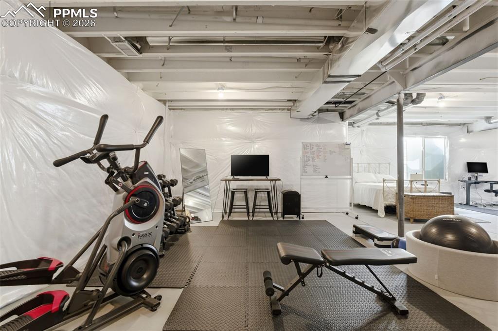 Image 34 of 50: Unfinished basement used as a gym, spare bedroom, and office space