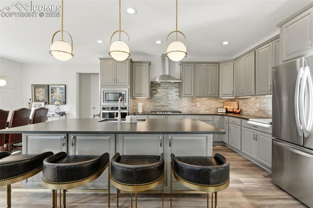 Image 9 of 50: Kitchen showcasing Hinkley lighting, backsplash, granite counters, upgraded