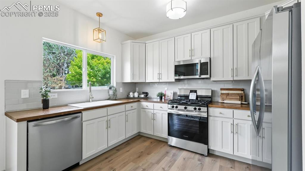 Image 17 of 50: Appliances include a side by side refrigerator, gas range oven, microwave,