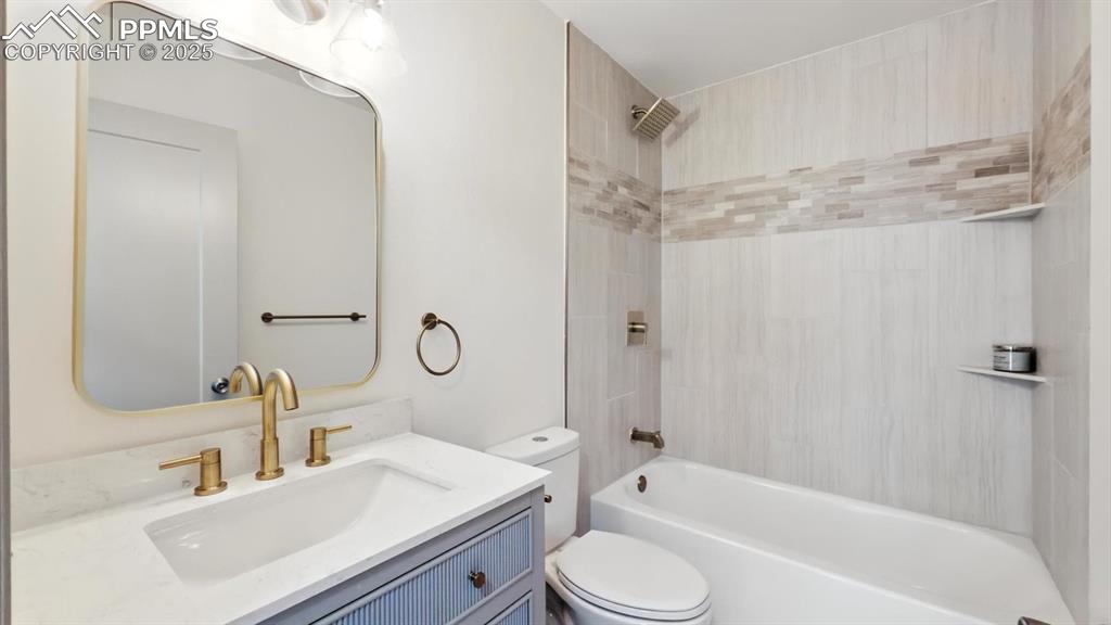 Image 24 of 50: Updated upper level full bathroom with vanity, mirror, and tiled tub/shower
