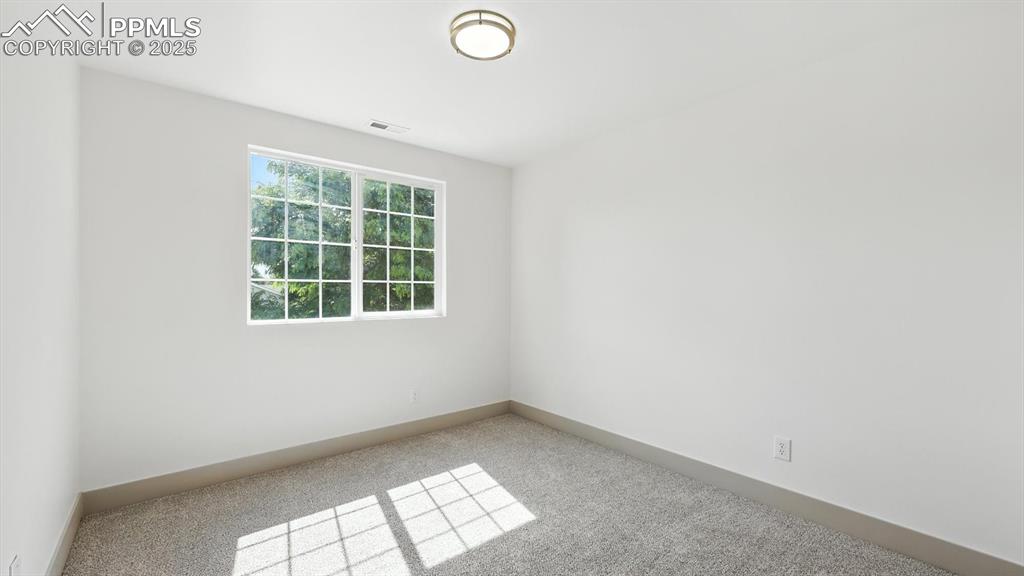 Image 29 of 50: Upper level bedroom #2 has neutral carpet and a new light fixture.