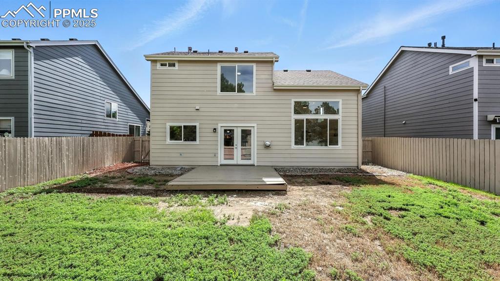 Image 39 of 50: Spacious, fenced backyard with wood deck for outdoor dining and relaxation.