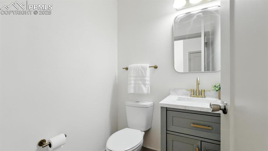 Image 7 of 50: Convenient powder bathroom with vanity and mirror.