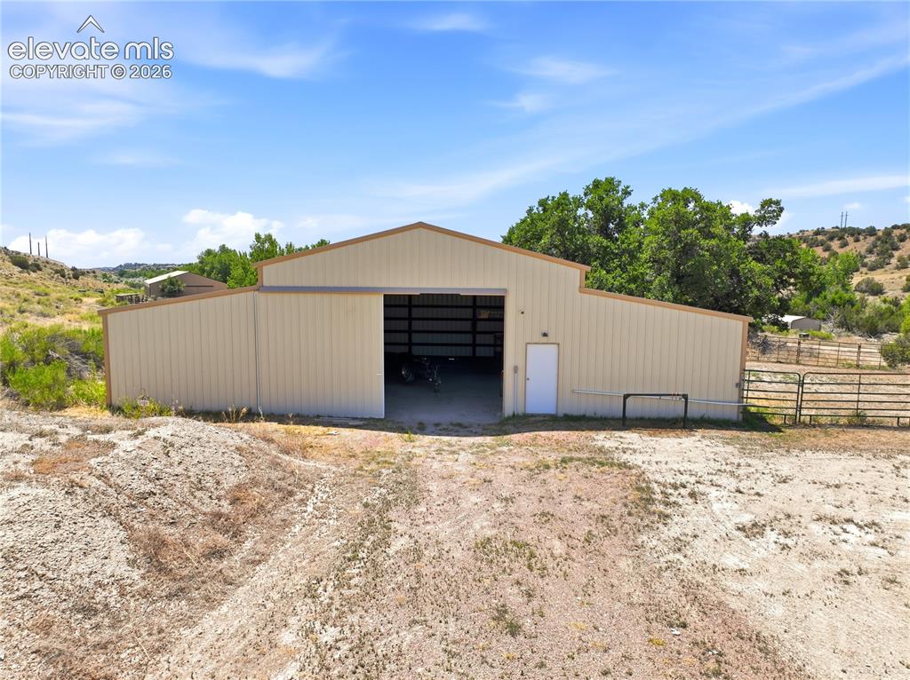 Image 13 of 49: Metal-sided barn structure with a large sliding door, a single white entry