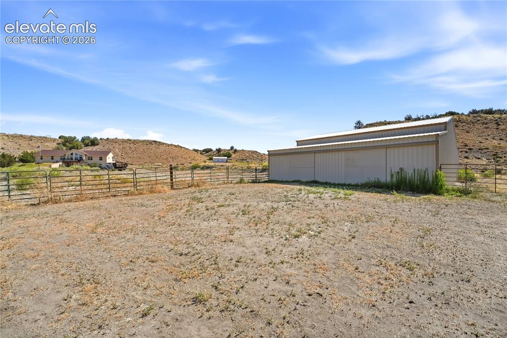 Image 14 of 49: Expansive property featuring a large metal-sided outbuilding with a metal r