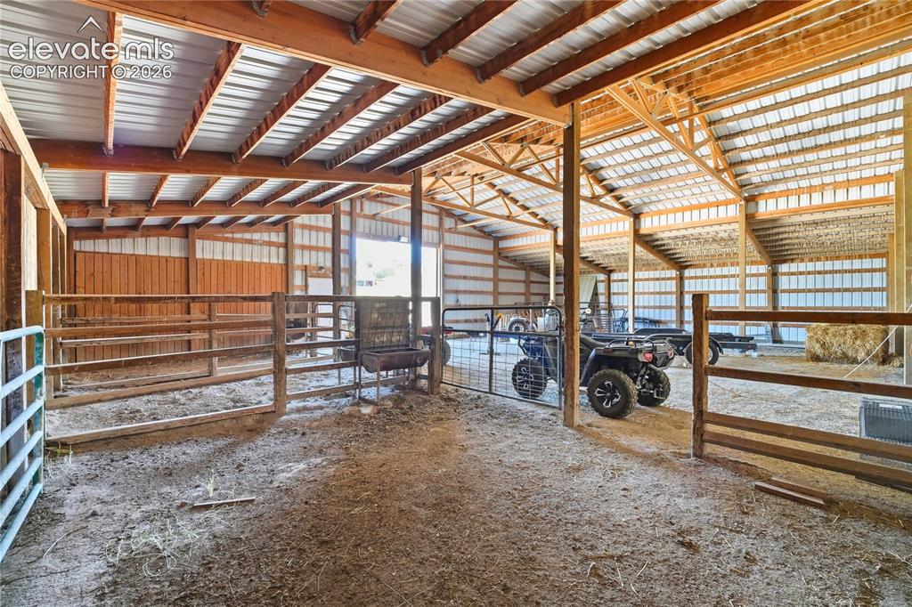 Image 17 of 49: Barn structure with wooden framing, metal roofing, and multiple stalls with