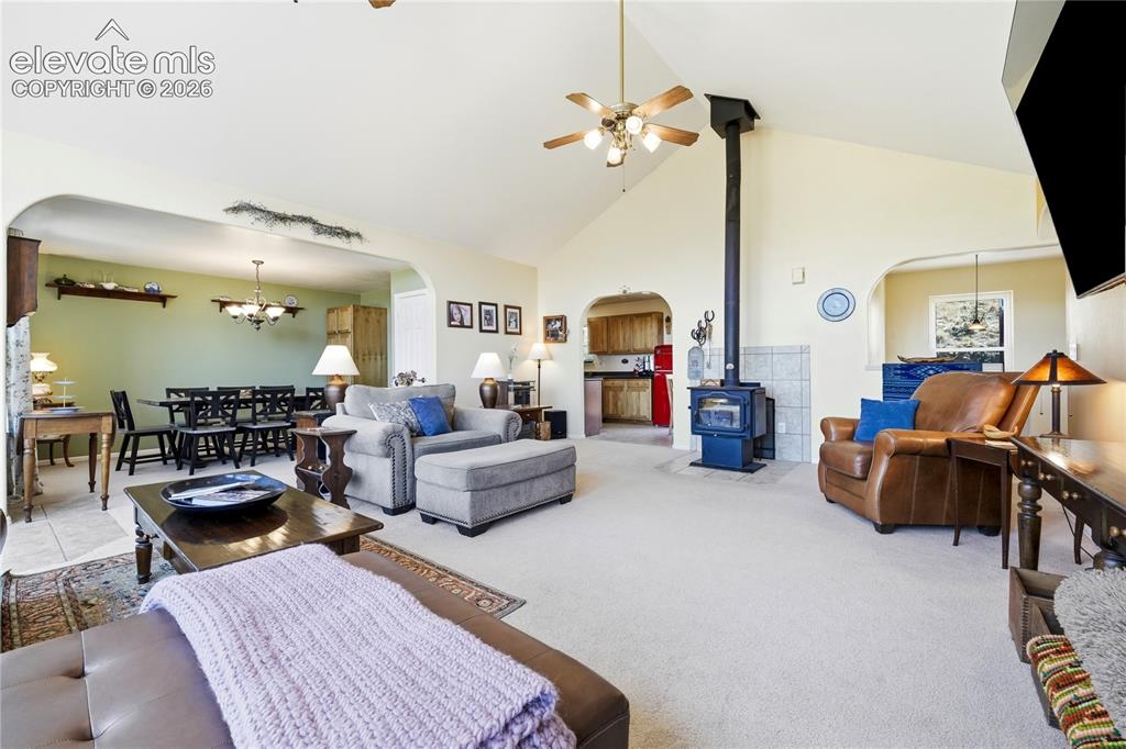 Image 26 of 49: Vaulted ceiling, ceiling fan, wood-burning stove with tile surround, arched