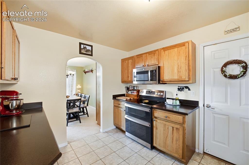 Image 28 of 49: Kitchen featuring wood cabinetry, stainless steel microwave, black electric