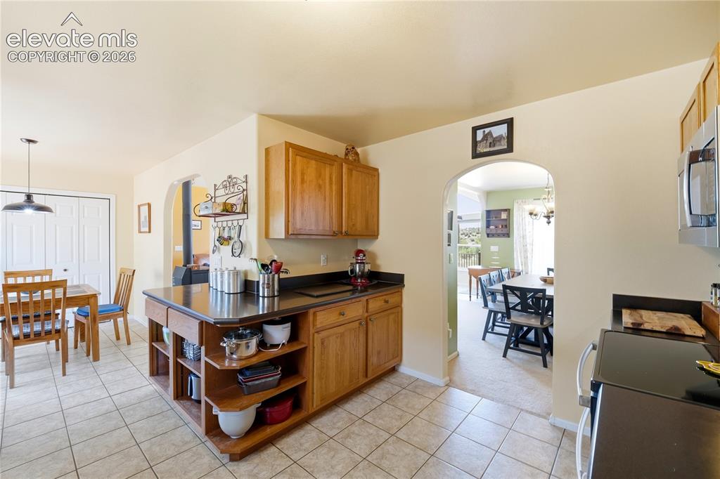 Image 29 of 49: Kitchen featuring wood cabinetry, dark countertops, a stainless steel micro
