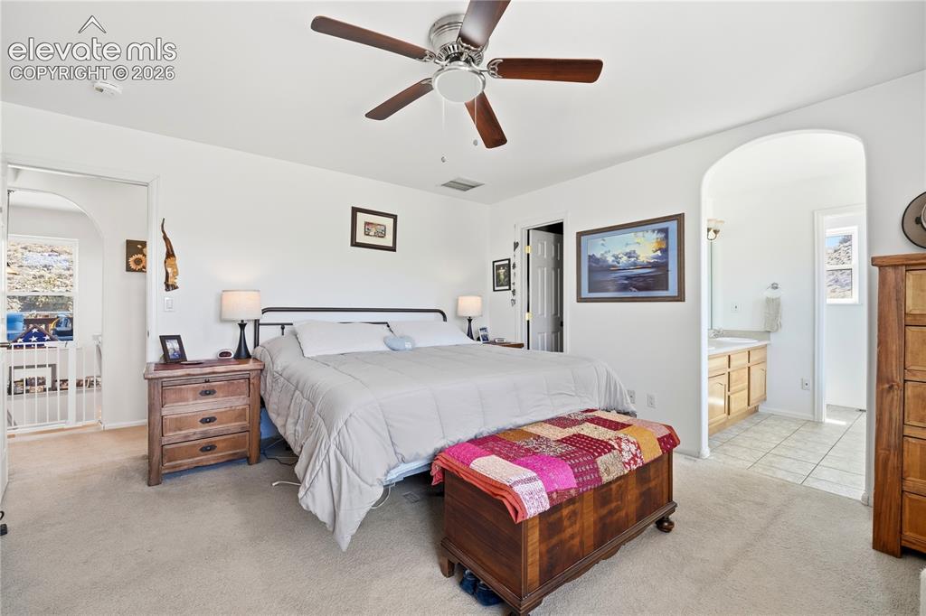 Image 32 of 49: Carpeted flooring, ceiling fan, arched doorway, and white walls