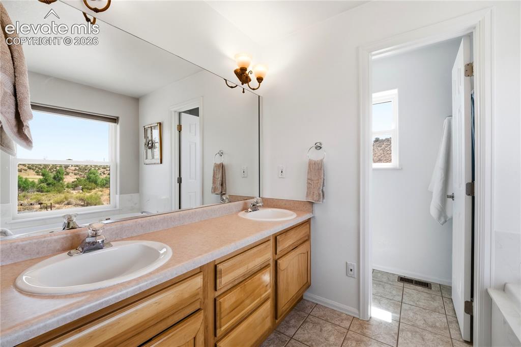 Image 33 of 49: Bathroom featuring a dual vanity with light wood cabinetry, a large wall-mo