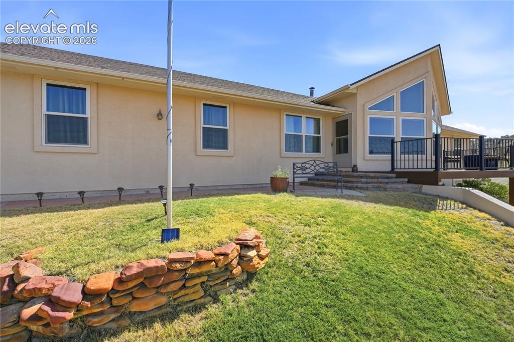 Image 7 of 49: Stucco exterior with multiple windows, elevated deck featuring dark railing