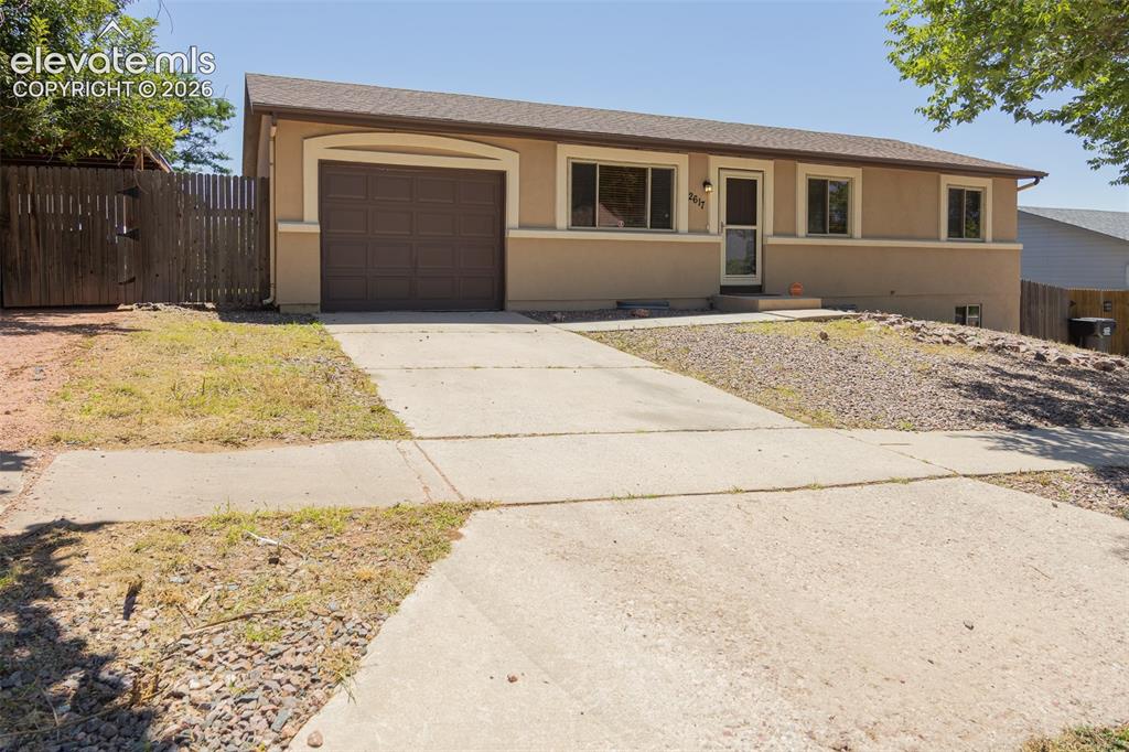 Caption: Contemporary ranch-style residence featuring a two-tone stucco exterior, an attached garage with an 