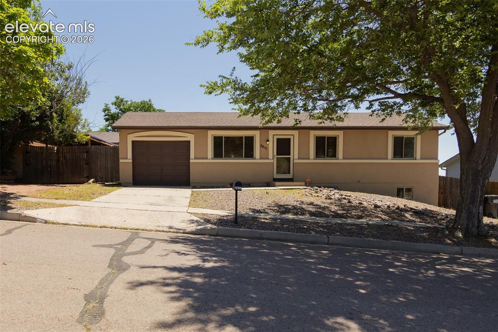 Image 2 of 38: Split-level residence featuring a two-tone stucco exterior, attached garage