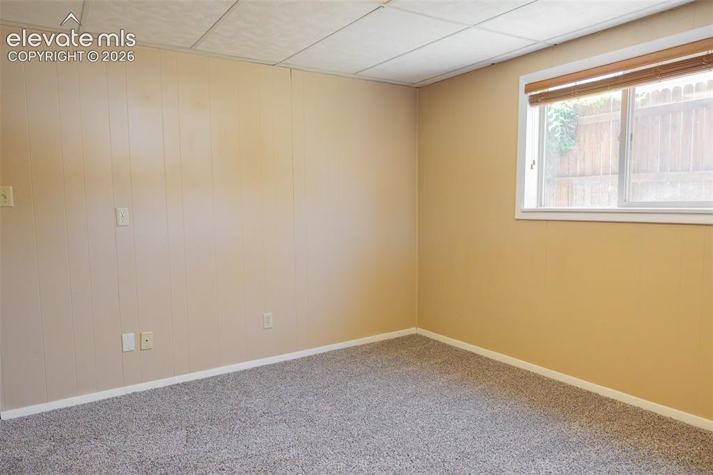 Image 33 of 38: Carpeted room with a drop ceiling and two-tone wall finishes, including pan