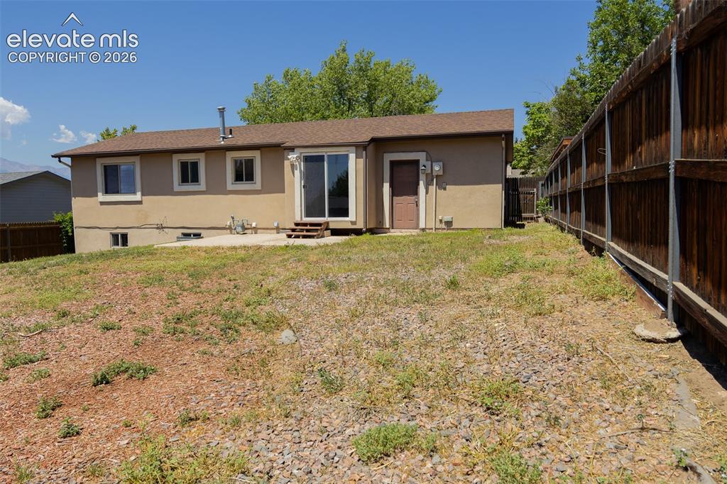 Image 5 of 38: Rear exterior featuring a stucco finish, sliding glass door, a privacy fenc