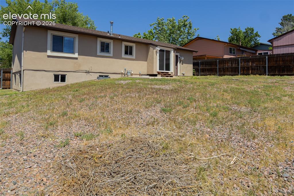Image 6 of 38: Expansive backyard with a sloped landscape and mature trees