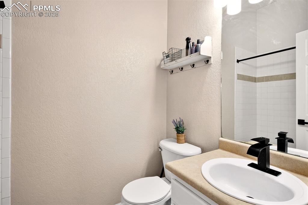 Image 17 of 21: Full bath with a textured wall, vanity, and a shower