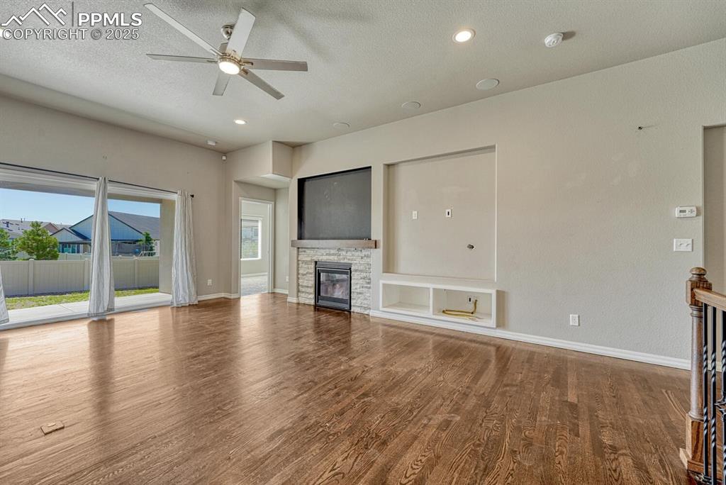 Image 10 of 45: Step into the family room, where a ceiling fan, stone fireplace, and stunni
