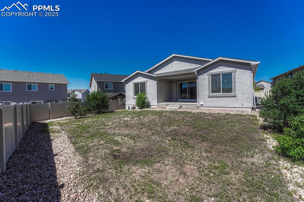 Image 35 of 45: The back of the property showcases charming stucco siding and a safely encl
