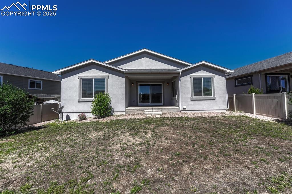 Image 36 of 45: The back of the property showcases charming stucco siding and a safely encl