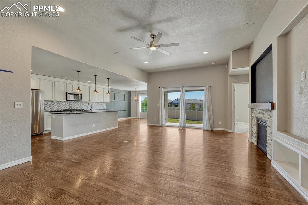Image 8 of 45: Step into the family room, where a ceiling fan, stone fireplace, and stunni