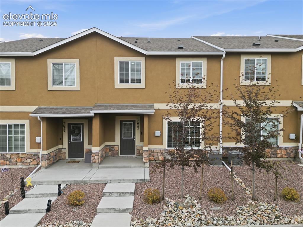 Image 1 of 44: Multi-story facade featuring warm stucco siding and stone veneer accents