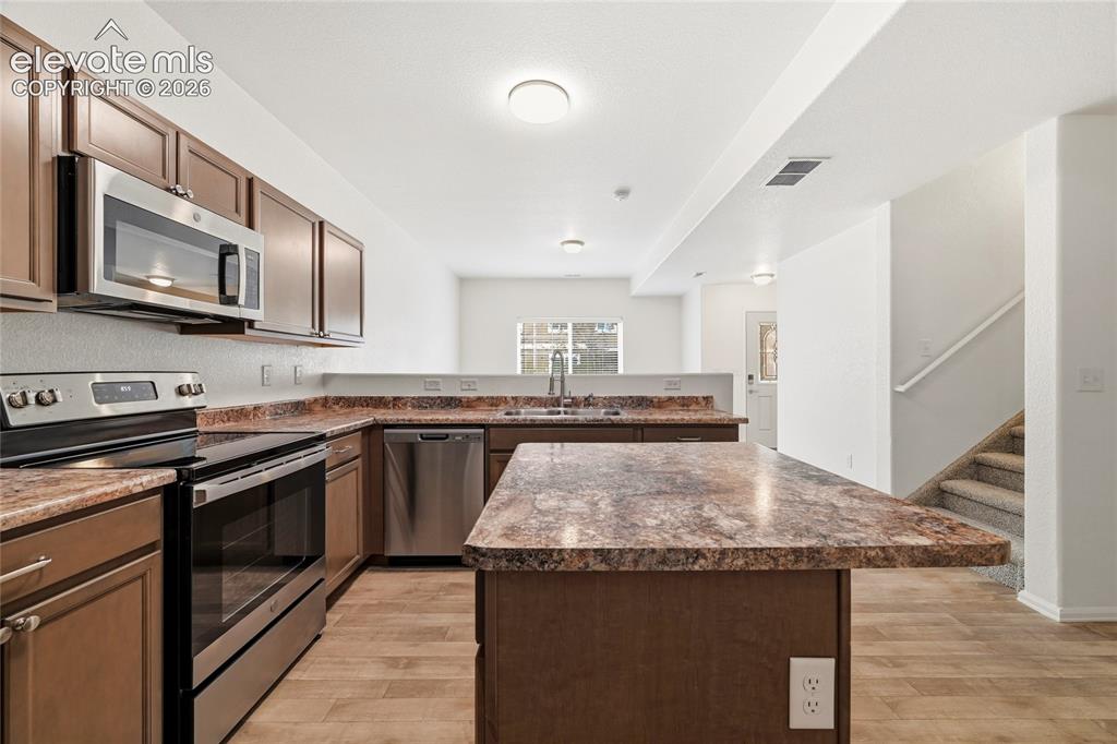 Image 12 of 44: Open-concept kitchen featuring wood-finish flooring, stainless steel applia