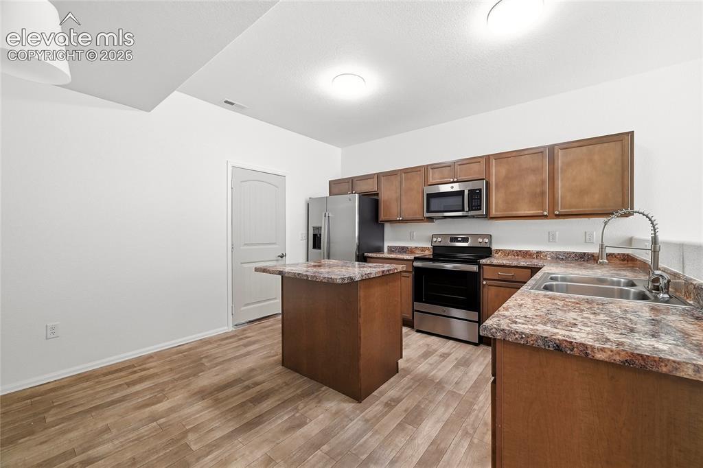 Image 13 of 44: Kitchen featuring wood-finish flooring, warm-toned cabinetry, and stainless