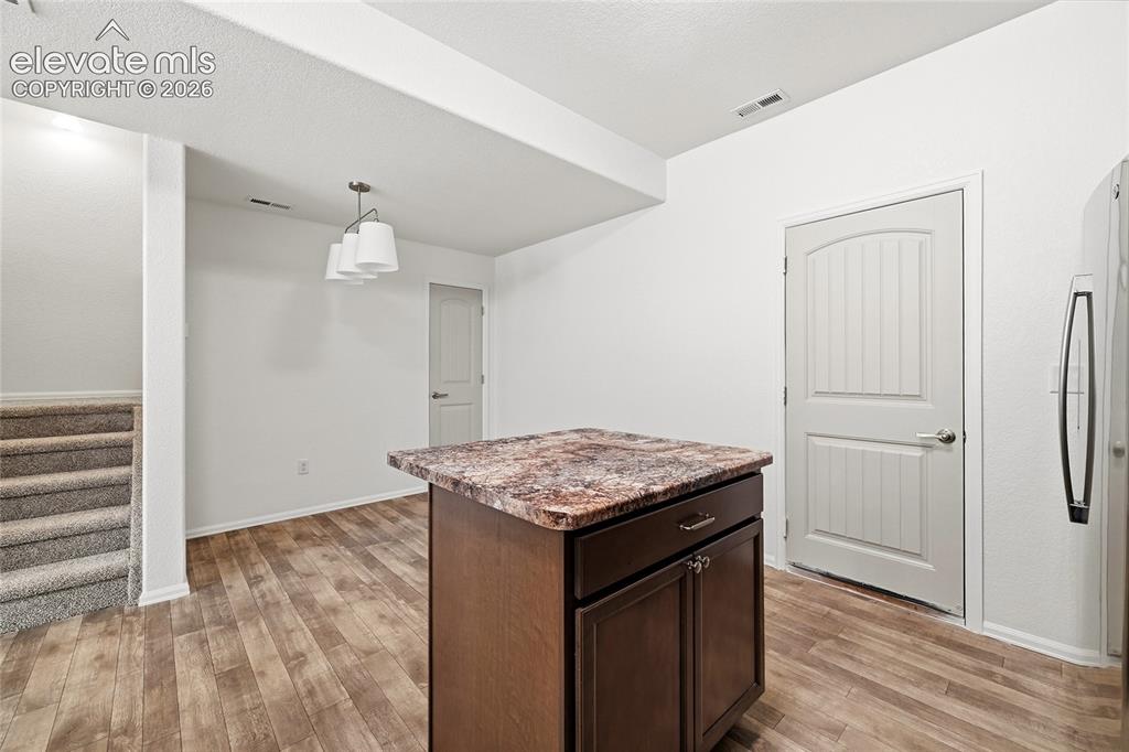 Image 17 of 44: Kitchen island with a granite-style countertop and dark wood-finish cabinet