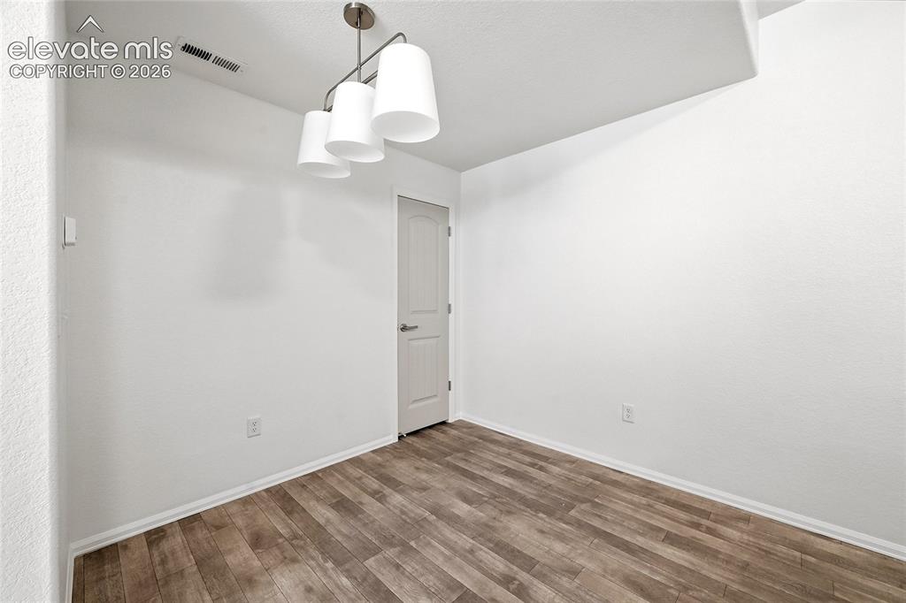 Image 18 of 44: Interior space featuring wood-finish flooring, white walls, and a contempor