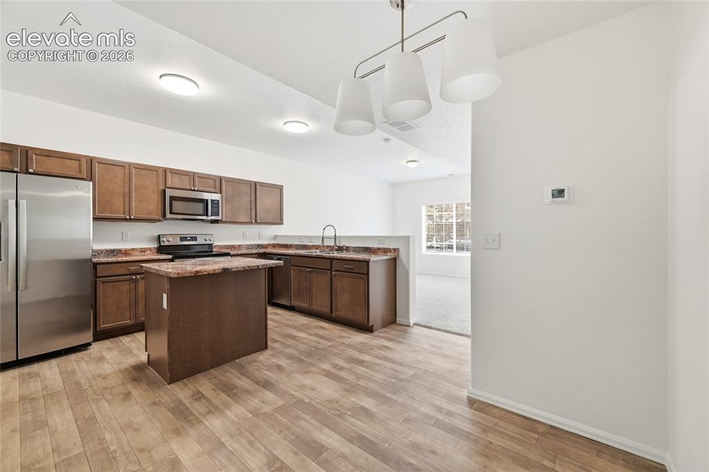 Image 19 of 44: Kitchen featuring wood-finish flooring, dark wood cabinetry, a central isla