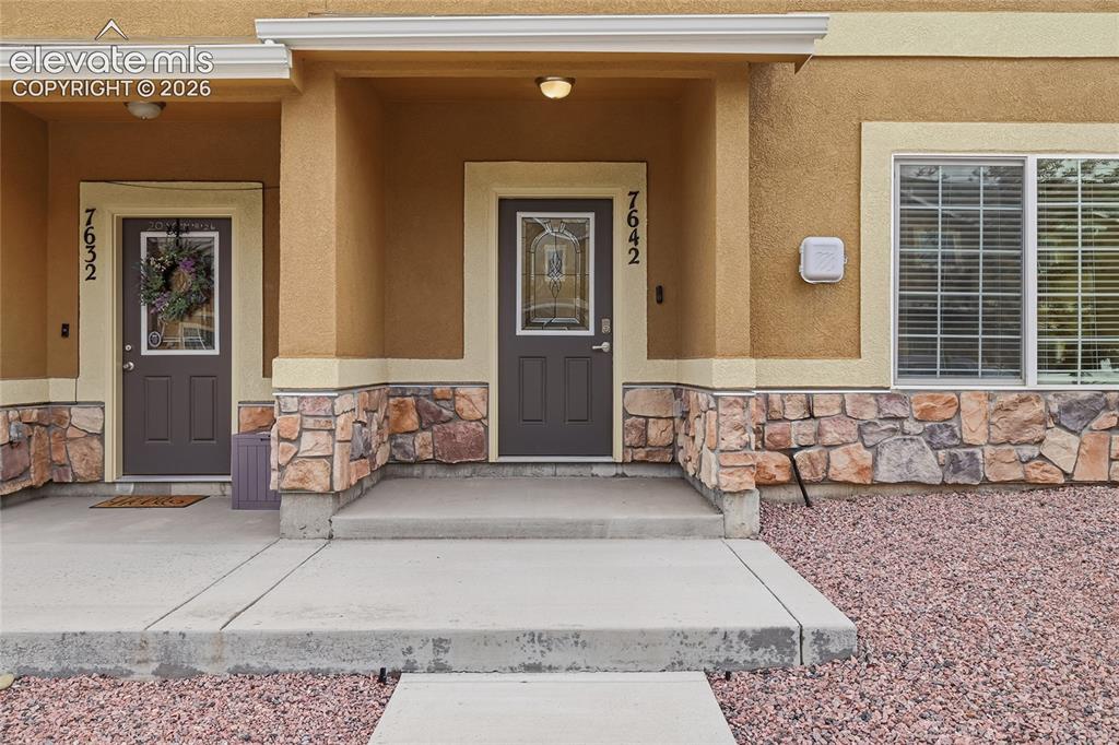 Image 2 of 44: Stucco exterior with stone veneer accents, covered entry, and concrete walk
