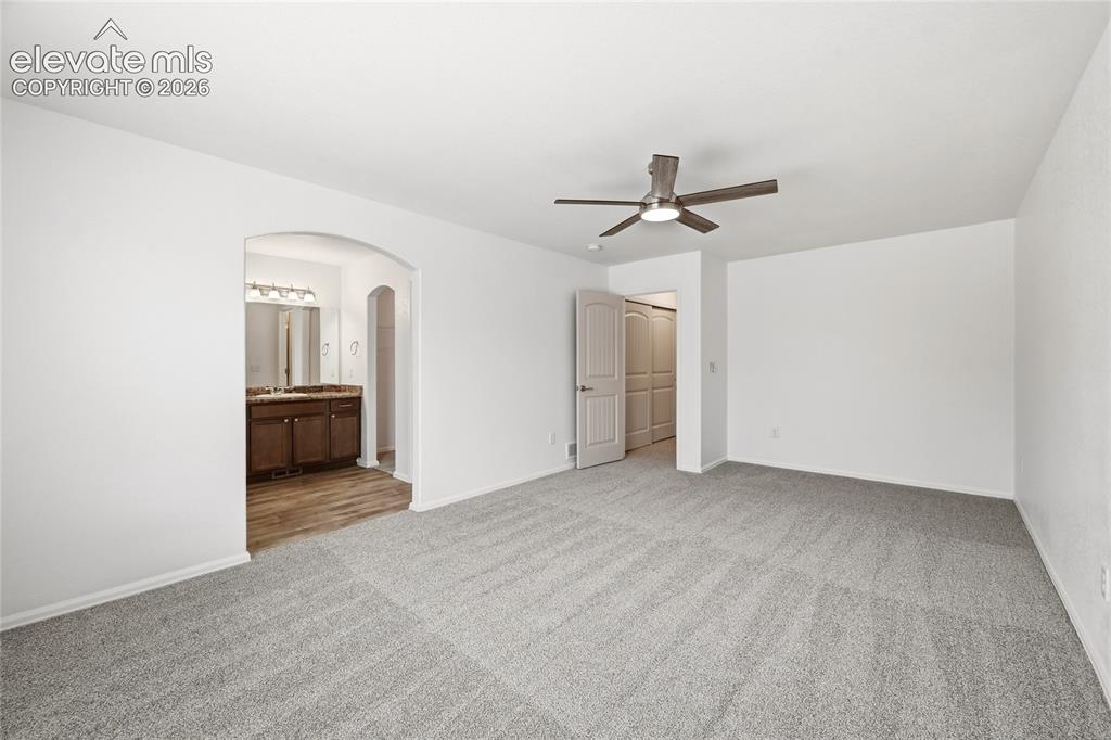 Image 21 of 44: Expansive room with neutral carpeting and a ceiling fan with integrated lig