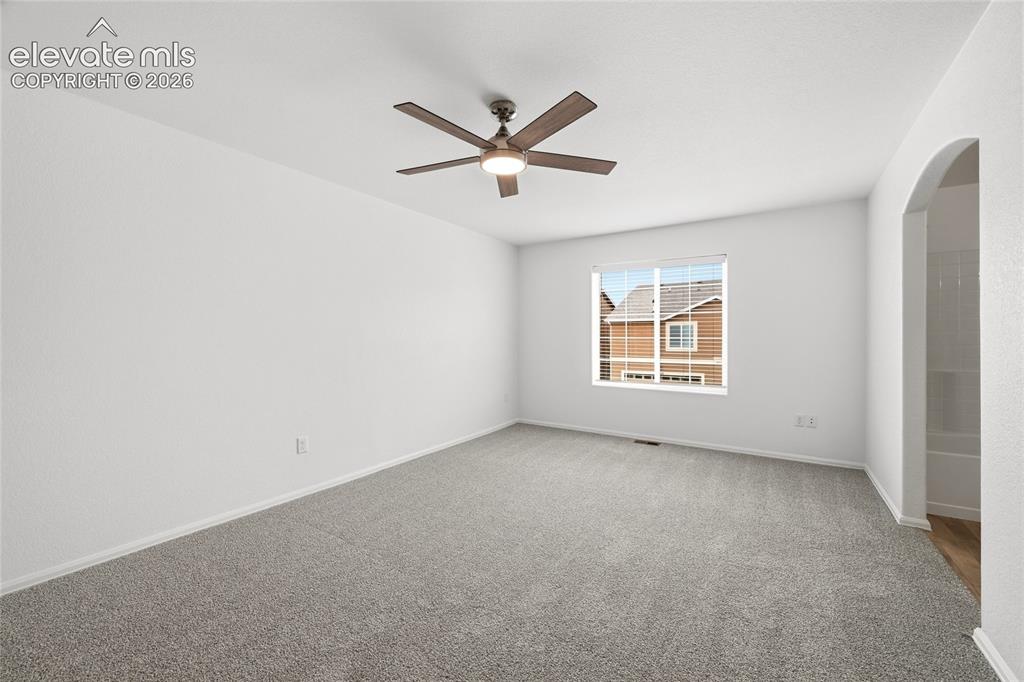 Image 22 of 44: Spacious room featuring neutral carpeting, white walls, a ceiling fan with 