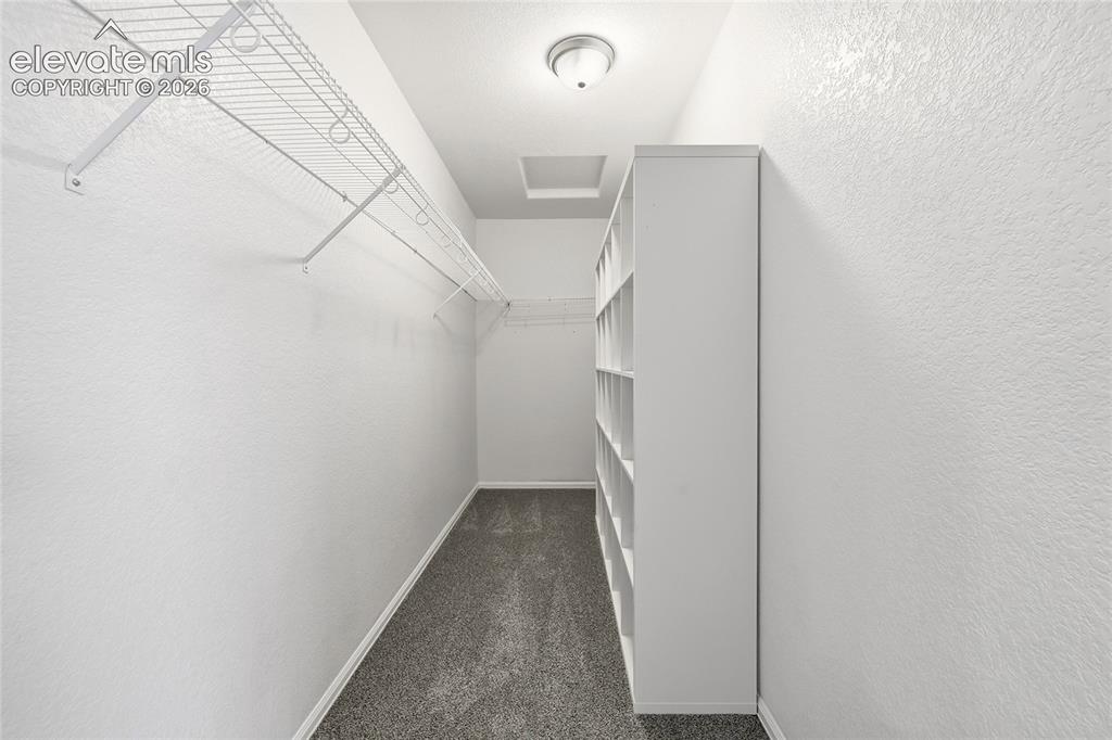 Image 26 of 44: Walk-in closet featuring wire shelving, built-in shelving unit, overhead li