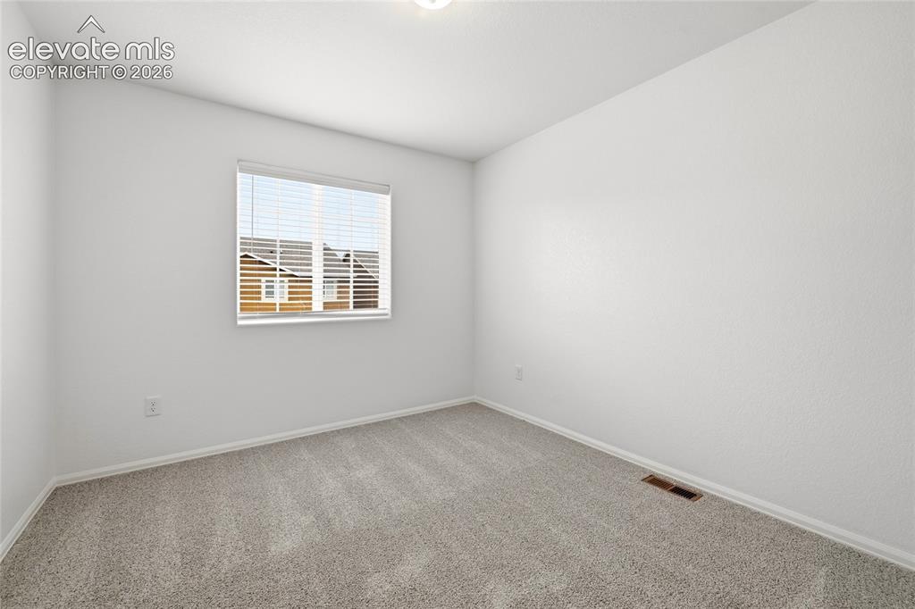Image 29 of 44: Neutral-toned carpeting paired with white walls, a single window with blind