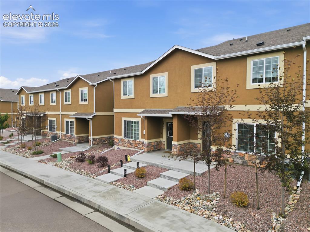 Image 3 of 44: Row of townhomes featuring stucco exteriors with stone accents, multiple la