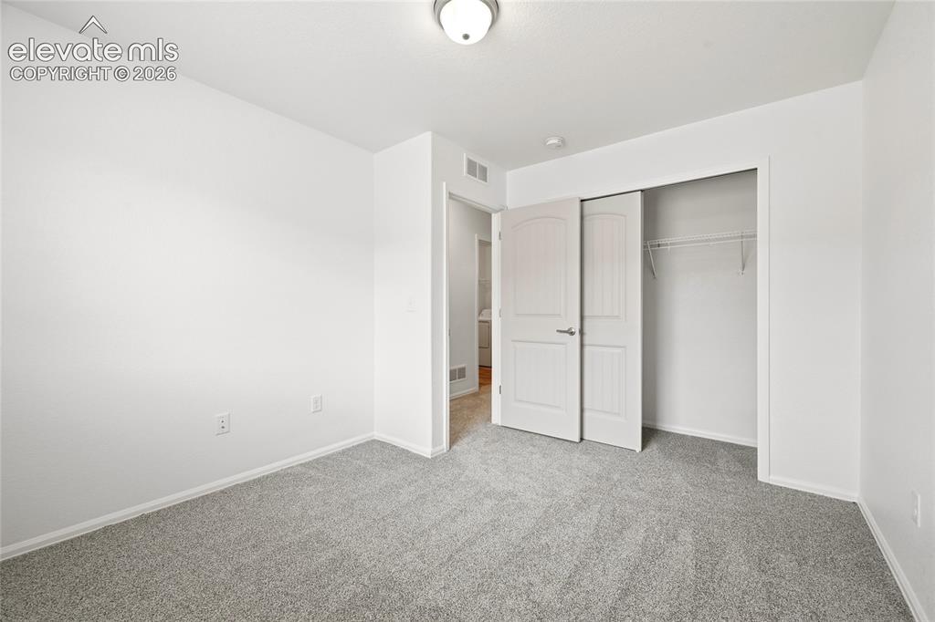 Image 30 of 44: Neutral-toned room featuring grey carpet flooring and white walls